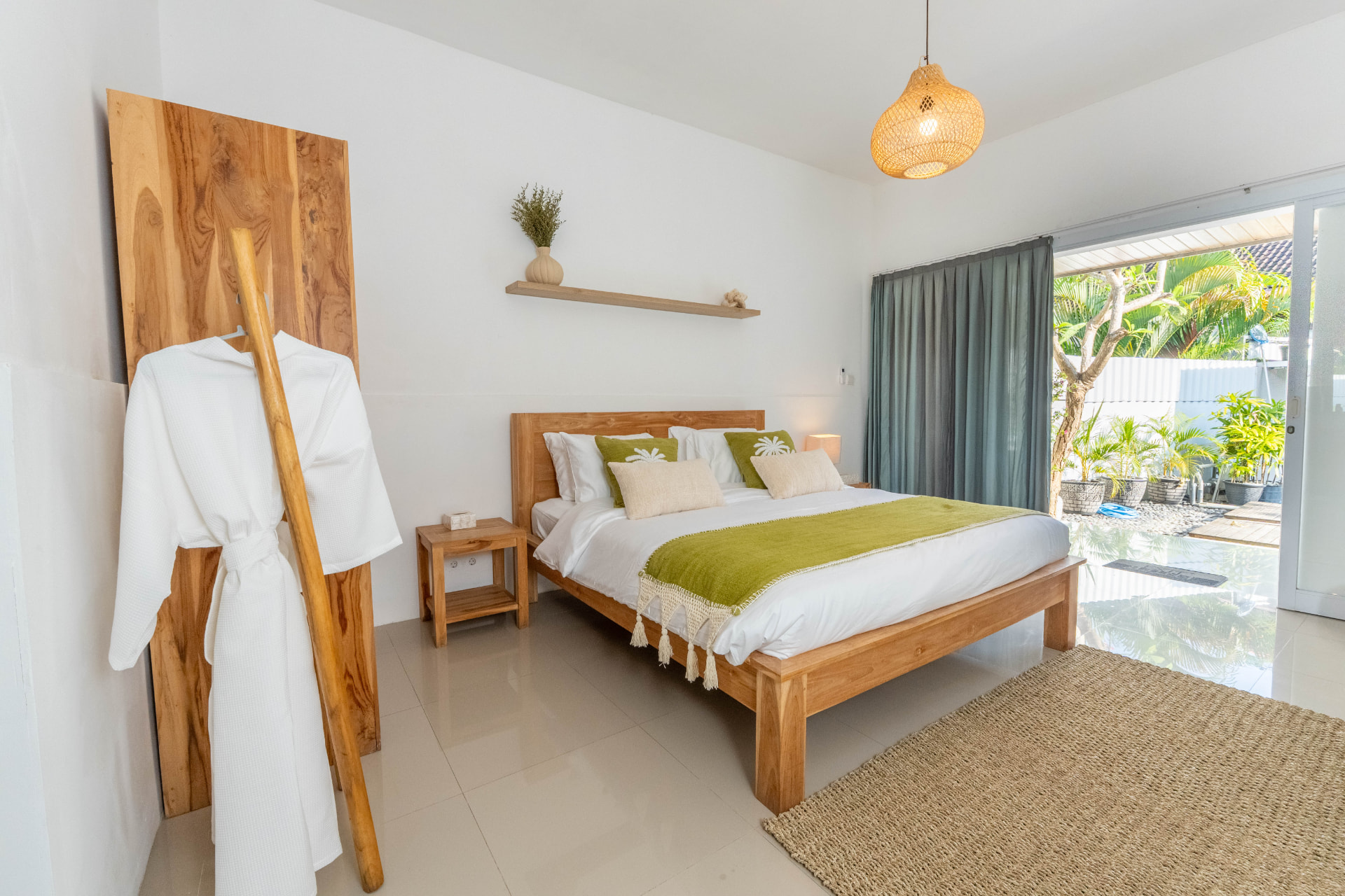 Bright Bali villa bedroom with teak furniture and garden pool view for property marketing