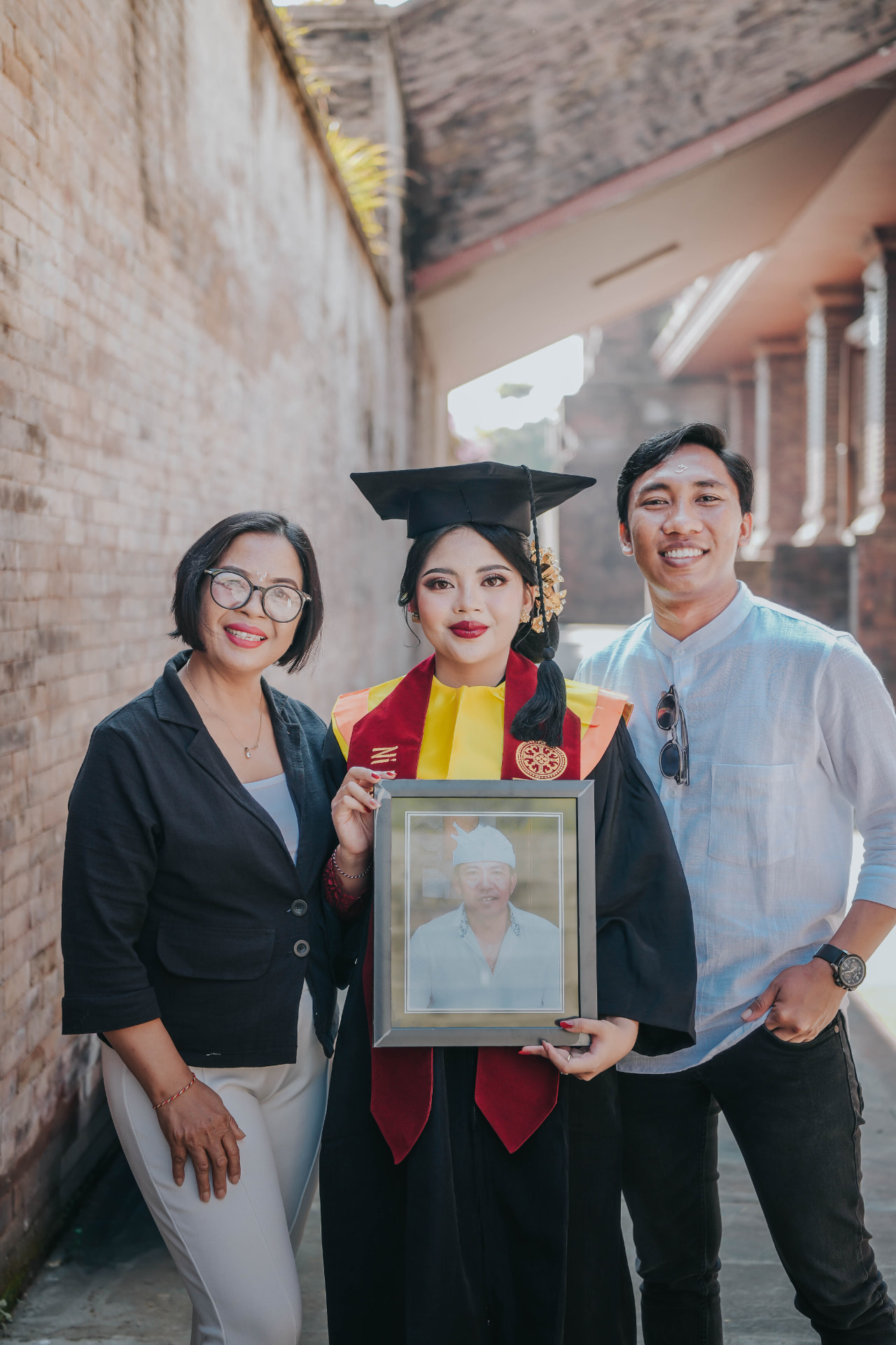 Bali family portrait — graduation celebration with family in a traditional Balinese alley